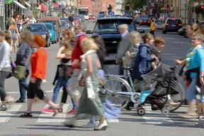 Människor vid övergångsställe på trafikerad gata i Stockholm.