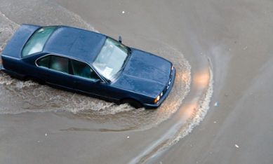 Bil som åker på översvämmad väg