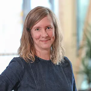 Kvinna med ljust hår ler mot kameran.