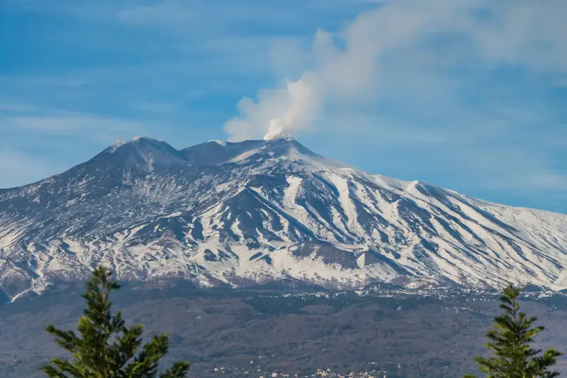 Utbrott med rök från vulkanen Etna i vinterlandskap.
