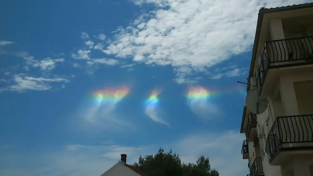 Cirkumhorisontbågen syns som regnbågens färger i molnslöjor på blå himmel.