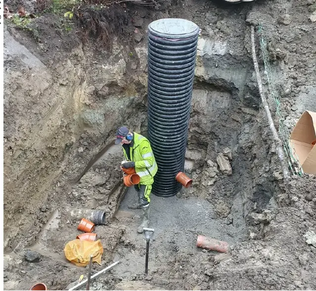 Man i grop som utför underhåll av en brunn.