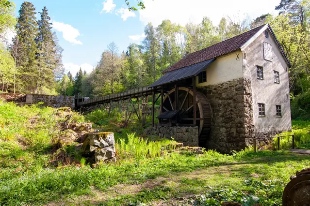 Dammbyggnad med överledning i grönskande miljö.