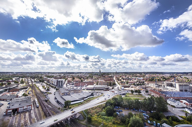 Flygbild över ett soligt Linköping med tågstation till vänster, Steningerondellen och domkyrkan rakt fram.