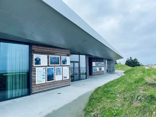 Fotoutställning på fasaden till en byggnad som ligger alldeles intill en strand.