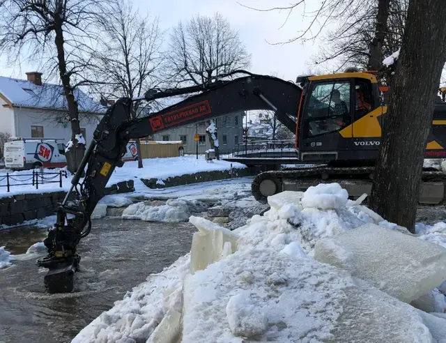 Foto på grävskopa, is och å