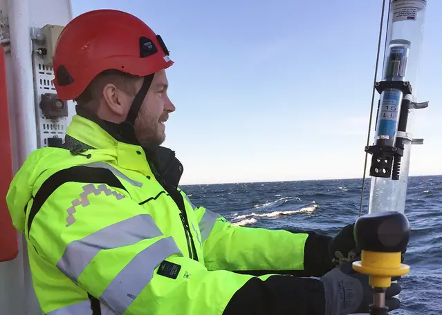 Bild på man i varselkläder som blickar ut över havet.