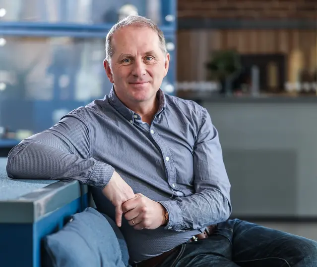 Man som sitter i en soffa och ler in i kameran.