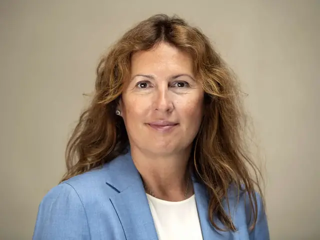 Kvinna i brunt hår ler mot kameran.