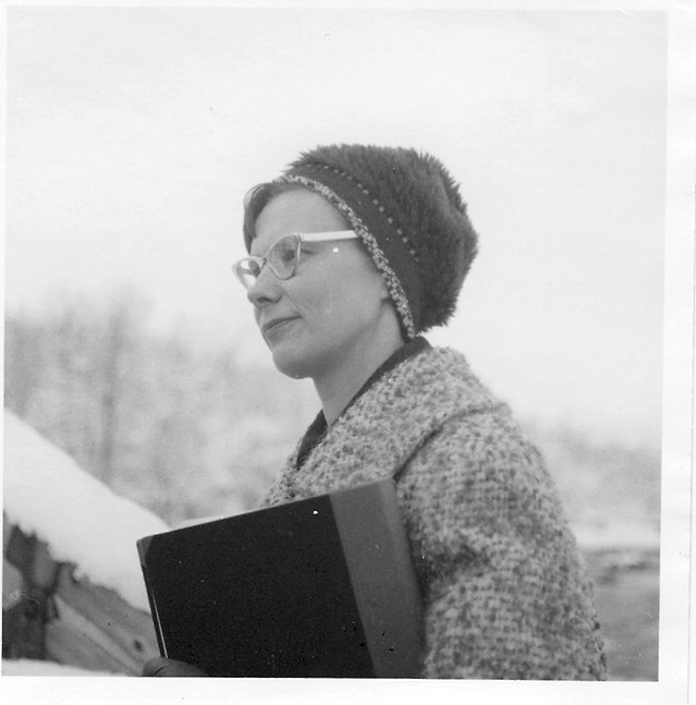 Kvinna i mössa med bok under arm.