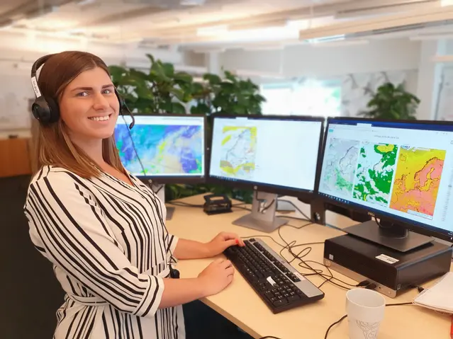 Tjej som står framför dator med väderprognoser.