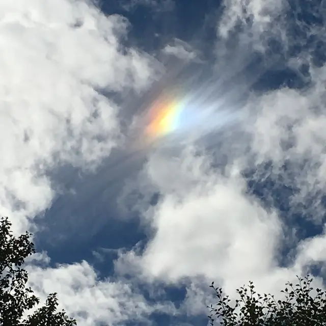 En färggrann bisol på en himmel med växlande molnighet och sol.